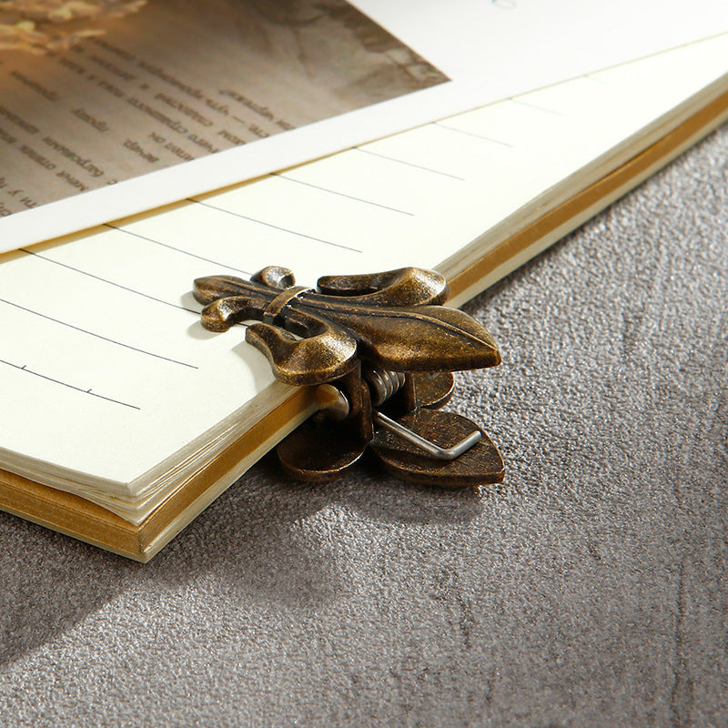 Collage of Aged Antique Bronze Fleur-de-lis journal clips. Showing the hand-held size, a single clip on vintage paper, and a decorative pair of heavy-duty bronze clamps.