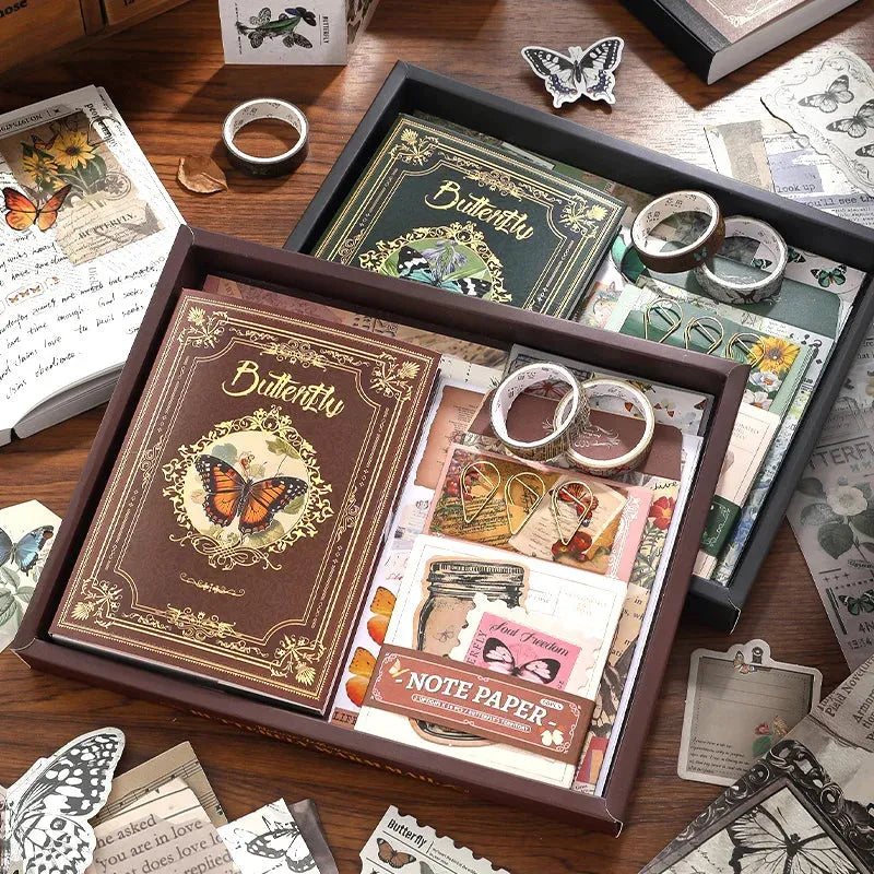 Display of the vintage butterfly aesthetic journal gift box collection, showing both the Nature's Whispers brown kit and the Emerald Forest green kit. Open boxes reveal premium washi tapes, notebooks, and ephemera for junk journaling.