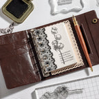 Leather journal decorated with vintage clear stamp impressions beside an ink pad – stamping in a travel journal