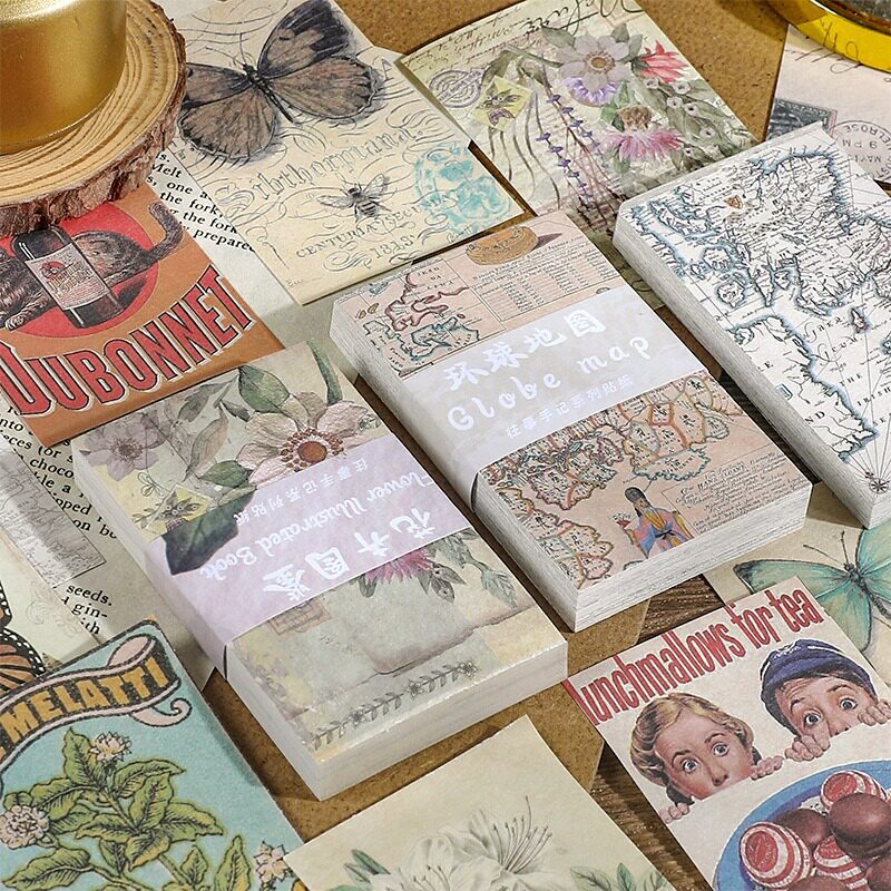 Close-up flatlay of butterfly travels, flower illustrated, globe map, and modern poster vintage paper bricks
