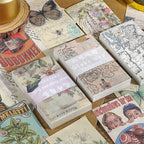 Close-up flatlay of butterfly travels, flower illustrated, globe map, and modern poster vintage paper bricks
