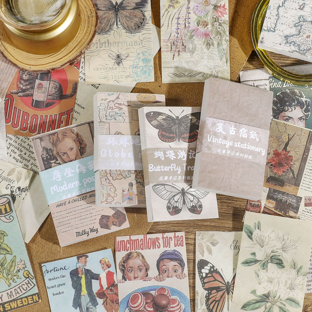Vintage ephemera paper collection with magnifying glass and candle featuring butterfly, floral, and map prints