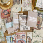 Vintage ephemera paper collection with magnifying glass and candle featuring butterfly, floral, and map prints