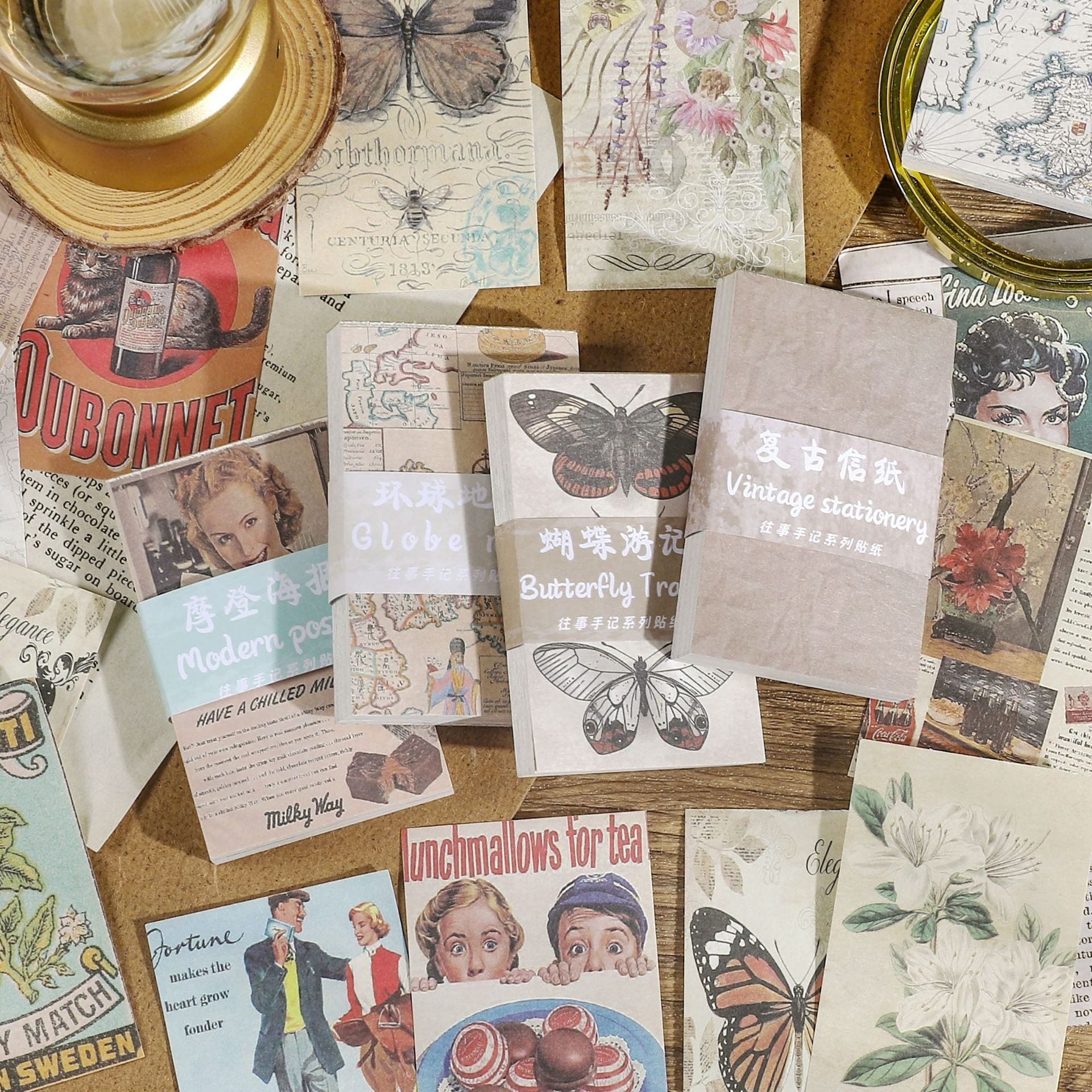 Vintage ephemera paper collection with magnifying glass and candle featuring butterfly, floral, and map prints