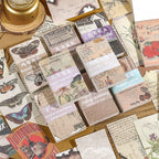 Eight vintage ephemera paper packs with butterfly, floral, map, and newspaper themes on cork board