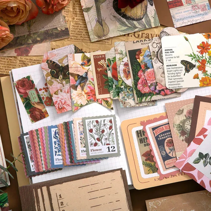 Close-up view of the vintage ephemera included in the floral journaling kit. Features colorful stamp-style stickers, butterfly and bird illustrations, and retro aesthetic paper tags perfect for Cottagecore junk journals.