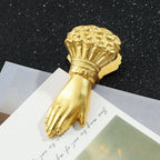 A stunning heavy-duty vintage gold metal journal clip shaped like a lady's hand holding a rose bouquet. Featuring a sparkling rhinestone ring, it rests on aesthetic paper cards, perfect for Cottagecore and Dark Academia desk setups.