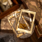 Close-up of vintage kraft paper collage frames featuring antique floral and clock designs, beautifully stacked on a glass jar for dark academia scrapbooking inspiration.