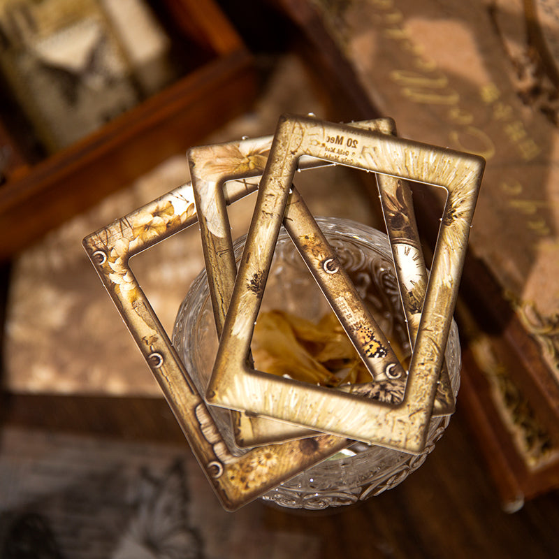 Close-up of vintage kraft paper collage frames featuring antique floral and clock designs, beautifully stacked on a glass jar for dark academia scrapbooking inspiration.