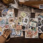 Six vintage postage stamp sticker packs scattered on dark wood desk with lace, showing botanical space and travel themes.