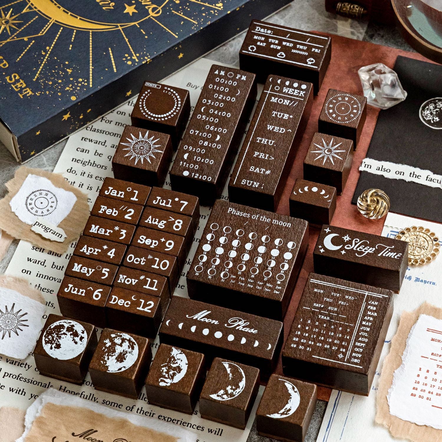 A detailed flat lay showcasing all 29 solid wood stamps from the celestial set. Features deep-etched rubber designs for months, days, times, and moon phases, perfect for mystic aesthetic bullet journaling.